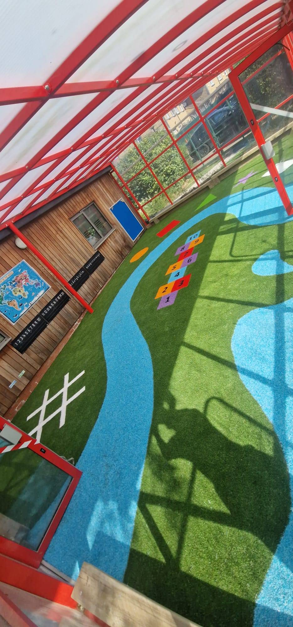 Colourful patterned artificial surface beneath a school canopy